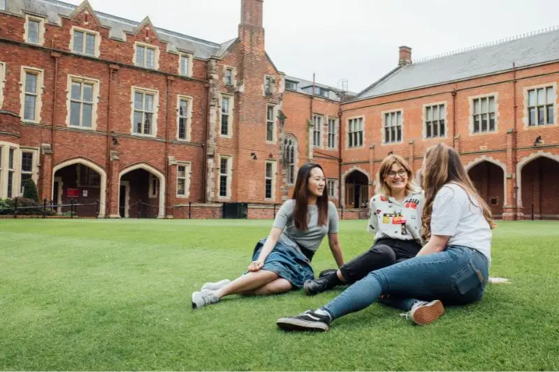 Three female students sitting on the grass at the quad